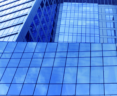 Ein modernes Hochhaus mit einer Fassade aus blau getönten Glaspaneelen.