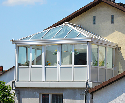 Ein Wintergarten mit Glasdach an einem Wohnhaus.